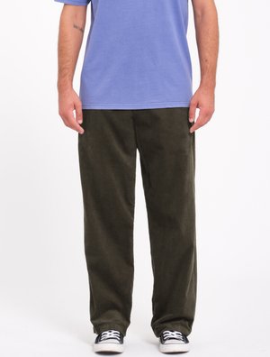 Grønne kordfløjl bukser med lige ben, der har en blød tekstur, båret med en blå T-shirt og sorte sneakers.