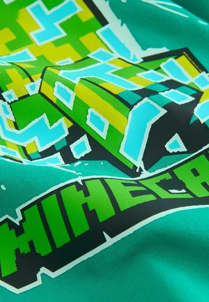 Green graphic t-shirt featuring a pixelated block design in yellow and blue, with the word "MINECRAFT" in bold black and bright green letters.