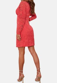 Korallfärgad spetsklänning med långa ärmar, blommönster, figurformad siluett, textil med struktur och midiboll längd. Matchad med snörskor.