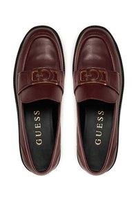 Mocassini in pelle bordeaux con logo in hardware dorato sulla cinghia, fodera interna nera e superficie liscia. Design con suola piatta e punta tondeggiante.