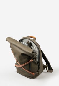 Zaino a forma di cilindro verde oliva con dettagli in pelle marrone, interno grigio, due tasche frontali e spallacci regolabili. Materiale resistente con finitura testurizzata.
