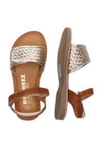 Brune og gyldne sandaler med en vævet metallisk rem, to justerbare ankelremme, struktureret sål og branding på indersålen.