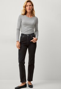 Zwarte high-waisted jeans met een recht gesneden pijp, gecombineerd met een aansluitend grijs langomslagtop. Gladde stoftextuur, minimale hardware.