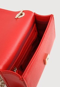 Bolso de mano de cuero sintético rojo con un acabado texturizado, hardware dorado y múltiples compartimentos en el interior para organización.