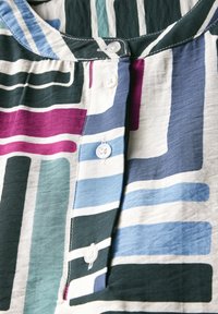 Camisa de botones multicolor con rayas horizontales y verticales en tonos de verde, azul, púrpura y blanco. Tejido suave con una textura lisa.