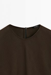 Dark brown fabric top with round neckline and visible back zipper, showing the inside label tag.