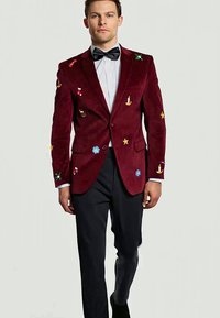 Bordeaux fluwelen blazer met kleurrijke geborduurde ontwerpen, twee voorzakken en een enkele knoopsluiting, gecombineerd met zwarte broeken.