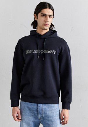 Marineblå hættetrøje med frontlogo, snor i hætten og ribbede manchetter. Kombinationen med lys blå denim giver et afslappet look.