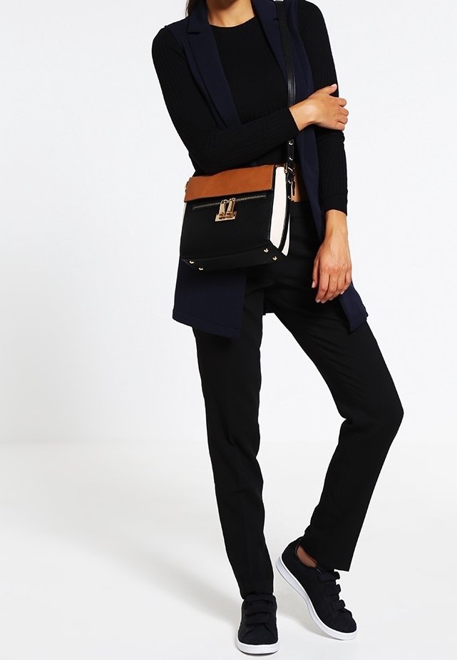 Torba noszona na krzyż, z czarną tkaniną, beżowym skórzanym wierzchem, złotymi akcentami oraz strukturalnym prostokątnym kształtem.