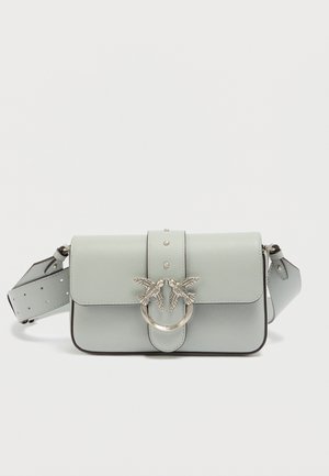 Sac à main en cuir bleu clair avec rabat, accents oiseaux en argent et détails cloutés. Comprend une sangle amovible de longueur réglable.