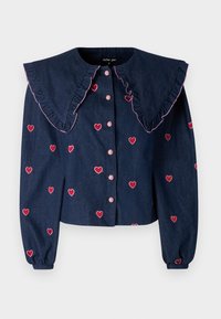 Τζιν μπλούζα με υπερμεγέθη ριγωτό γιακά, ροζ κέντημα καρδιάς και μπροστινή κουμπόκλειση. Μακριά μανίκια με ελαστικούς καρπούς.