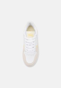 Hvit skinn sneakers med lysegule detaljer og beige semsket paneler. Har rund tå, snøring og perforerte detaljer.