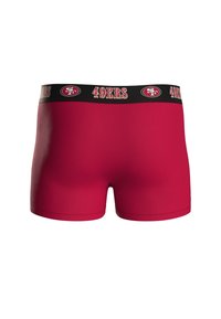 Boxer shorts rojos con una cinturilla negra que lleva el logotipo "49ERS" y acentos. La tela tiene una textura suave y un diseño ajustado.