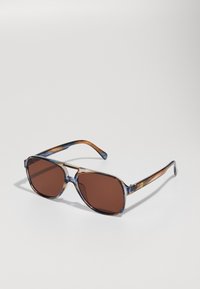 Ochelari de soare cu lentile rectangulare de culoare maro, rame transparente din scoică albastră și brațe maro cu dungi, având branding aurit pe lateral.
