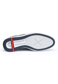 Schwarz-weiße Sneaker-Sohle mit strukturiertem Grip, versehen mit einem roten Akzentstreifen und einer glatten, geschwungenen Ferse. Das Profildesign ist linear und gemustert.