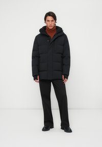 Chaqueta tipo puffer negra con capucha, con cremallera delantera y botones, textura acolchada, dos bolsillos laterales y un corte informal.
