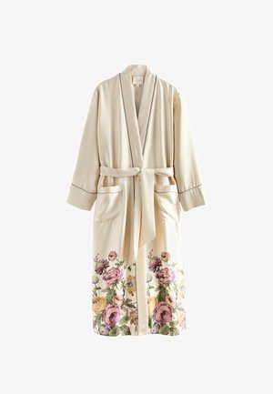 Cremfarbener, langärmeliger Bademantel mit Taillenkordel, zwei vorderen Taschen, lila Paspelierung und floraler Musterung entlang des unteren Saums.