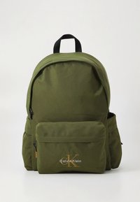 Green nylon backpack with a rounded top, front zip pocket, and subtle logo. Features black straps and accents, offering a smooth texture.