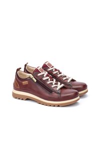 Scarpe in pelle marrone con chiusura a zip e lacci bianchi. Presentano suole in gomma beige spesse e un dettaglio logo sul lato.