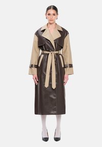 Bruine en beige leren trenchcoat met brede revers, tailleband en lange mouwen. Voorzien van knoopdetails en een ontwerp met volledige lengte.