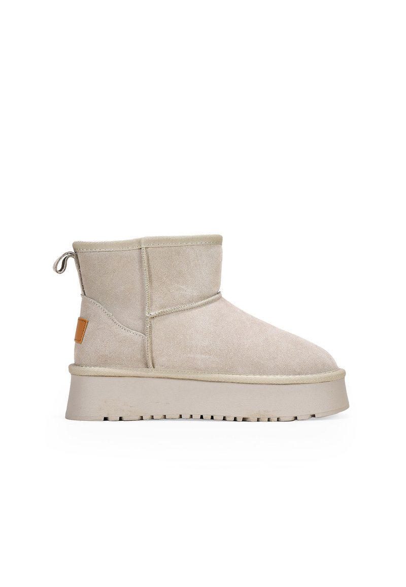 Stivaletto in suede beige con punta arrotondata, superficie sfumata, etichetta in pelle marrone contrastante e suola spessa e robusta con battistrada.