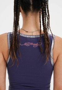 Top senza maniche blu navy con dettagli metallici argento, caratterizzato da "Ed Hardy" ricamato sulla parte posteriore in filo rosso a contrasto.