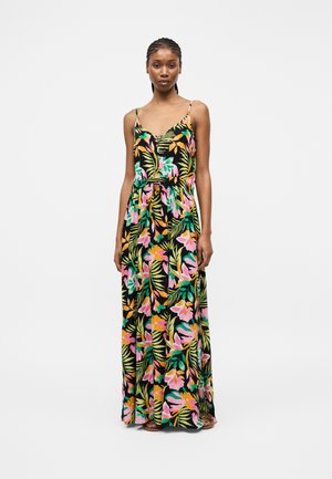 Femme aux cheveux tressés portant une robe maxi noire sans manches avec un imprimé floral tropical rose, orange et vert, debout devant un fond blanc.
