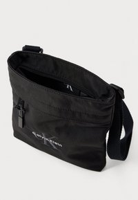 Borsa a tracolla in nylon nero con chiusura a zip, dotata di logo, tracolla regolabile e tasca interna per l'organizzazione.