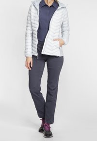 Lekka, pikowana szara kurtka z kapturem, w połączeniu z ciemnymi spodniami i czarnymi trampkami z fioletowymi sznurówkami. Posiada zamek błyskawiczny z przodu.