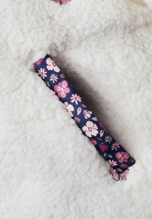 Biely fleece materiál so soft a nadýchanou textúrou, so kvetinovým vzorom v námorníckej modrej farbe s ružovými a bielymi kvetmi na vrecku.