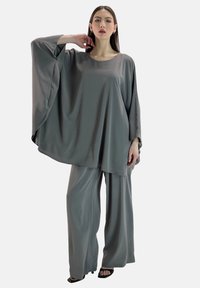 Graues, fließendes Zweiteiler-Outfit aus weichem Stoff; hat weit geschnittene Ärmel oben und lockere, weit geschnittene Hosen. Glatte Textur, minimalistisches Design.
