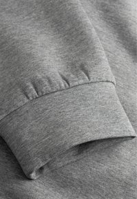 Grijze katoenen sweatshirt manchet met ribbelstructuur, heeft een zachte afwerking en een net gestikte zoom, benadrukt een casual en comfortabele ontwerp.