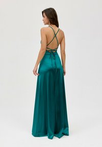 Tyrkysové saténové večerní šaty s odhaleným zádem a křížovými ramínky, nabízející splývavou siluetu a hladkou, lesklou texturu.