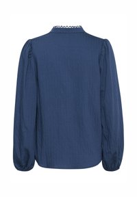 Sötétkék, hosszú ujjú ing texturált felülettel, lekerekített gallérral és puffos ujjakkal, melyet csipkés díszítés ékesít a nyaknál.