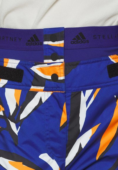 Blauwe en oranje gestreepte shorts met een brede paarse tailleband met drukknopen en haaksluitingen, gemaakt van een lichte stof.