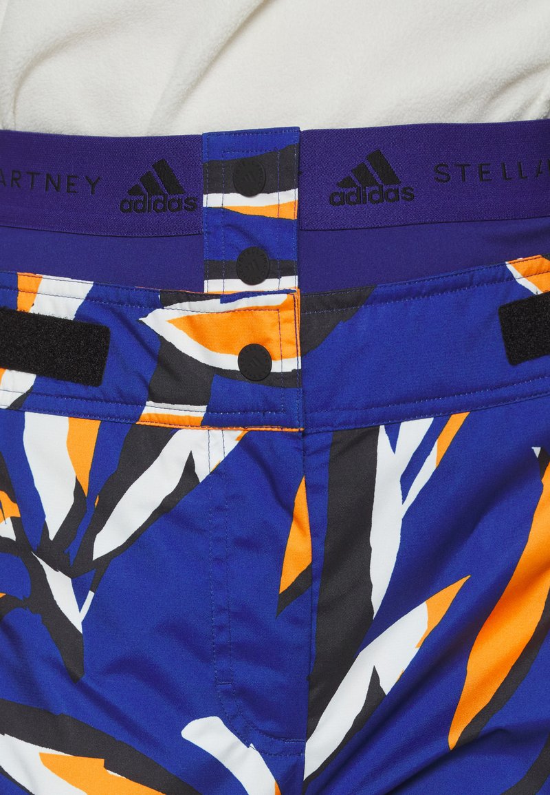 Pantaloni corti blu e arancioni con motivo, dotati di una larga cintura viola con chiusura a scatto e gancio, realizzati in un tessuto leggero.