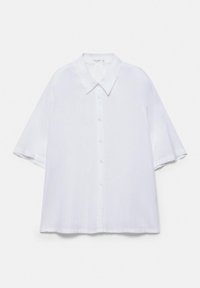 Chemise blanche à manches courtes avec boutons, larges manches et col pointu, posée à plat sur un fond blanc.