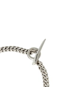Hopeaketju, jossa on kääntösolki. Ominaisuuksina toisiinsa limittyvät lenkit ja tuo "ALLSAINTS" kaiverrettuna solkeen. Suuri sileä pinta ja metallinen viimeistely.