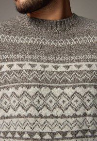 Pull en maille gris et crème avec un motif géométrique de losanges et de zigzags, doté d'un col rond côtelé et d'un tissu texturé.