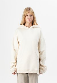 Roomy crèmekleurige hoodie van zachte stof, met een voorvak in kangoeroestijl en een trekkoordcapuchon. Getextureerde, comfortabele pasvorm.