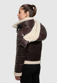 Daunenjacke mit einem dunkelbraunen Äußeren, einem cremefarbenen Fleece-Kragen und -Futter, Druckknöpfen und strukturiertem Material.