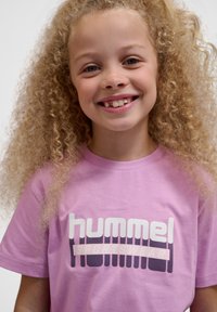 Rosa bomulds T-shirt med fed "hummel SPORTSWEAR" tekst i hvid med mørke accenter, korte ærmer og klassisk pasform.