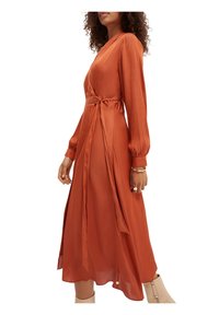 Robe enveloppante couleur rouille avec des manches longues, une taille nouée et un ourlet fluide. Texture lisse et tissu léger.