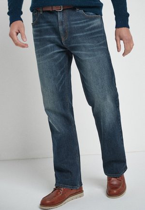 Pantalones vaqueros de mezclilla azul con corte recto, que presentan un diseño clásico de cinco bolsillos y costuras de contraste. Combinados con zapatos de cuero marrón.