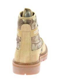 Stivaletto alla caviglia in suede color tan con tessuto camouflage, dotato di una tracolla con logo e una suola in gomma marrone. Il design include dettagli di cucitura e un tacco texturizzato.