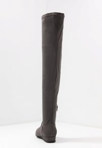 Bota gris de tela por encima de la rodilla con suela plana, textura suave, detalles de costura y cremallera en el costado. Sin patrones ni acentos visibles.