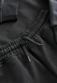 Sort sweatshirt med elastisk talje, justerbare snore med metalspidser, tekstureret stof og ribbede manchetter.