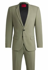 Oliven grøn suit med en struktureret blazer og matchende bukser. Har en enkelt knaplukning og flade forlommer. Indersiden er sort.