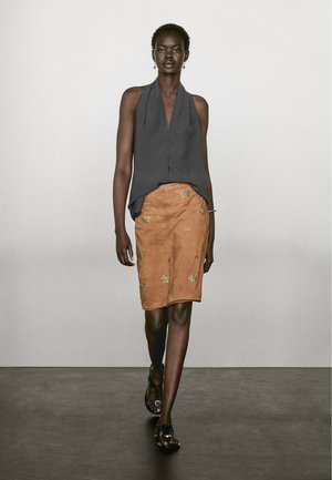 Sleeveless gray top, A-line design, paired with a tan suede skirt featuring gold embroidered leaf patterns and black sandals.