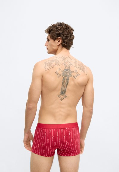 Červené bavlnené boxerky so vzorom opakujúceho sa nápisu "love" a pruhovaným dizajnom. Hladká textúra s priliehavým strihom a elastickým pásom.